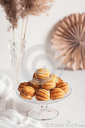 Russian traditional homemade cookies Nuts with condensed milk on glass stand on background of paper decor and reeds in vase White Stock Photo