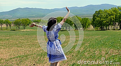 Russian young woman in dress in the Slavic style running and waving her hand to the nature against the background of green field Stock Photo