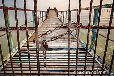 Rusted chain link and padlock close metal bars of old pier Stock Photo