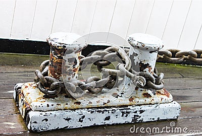 Rusted Dock Cleats with mooring chains attached - grunge -flaking white paint - at marina Stock Photo