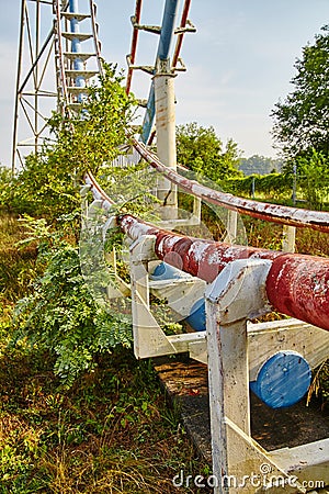 Rusted rails of an abandoned roller coaster with green leaves and shrubs Stock Photo