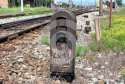 Rusted railway signal lights with position marker and red light on with train station in background Stock Photo