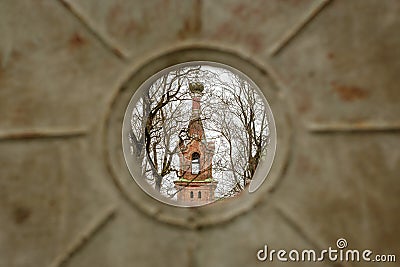 Glimpse of Divinity: Church Tower Through Metal Fence in Kuldiga, Latvija Stock Photo