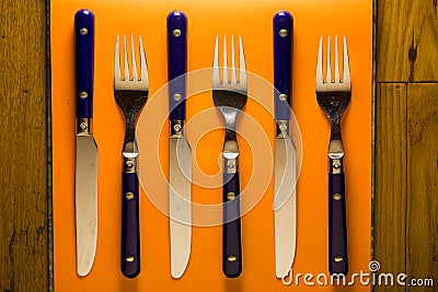 Rustic blue silverware on orange setting with wooden background Stock Photo