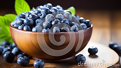 Rustic clay bowl filled with ripe blueberries and fresh spearmint placed on a wooden table Stock Photo