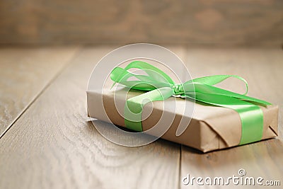 Rustic craft paper gift box with green ribbon bow on wood table Stock Photo