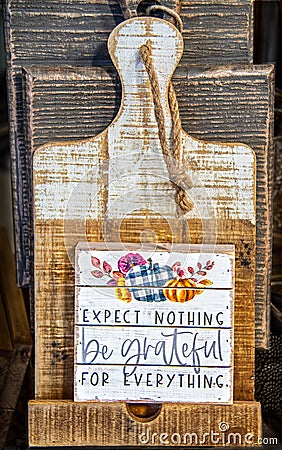 Rustic Cuttingboard with rough wooden plaque in front that says Expect Nothing be grateful for everything - Thanksgiving motif Stock Photo