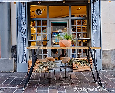 Rustic iron and wood table in front of the door of a bar with pots above and hanging Editorial Stock Photo