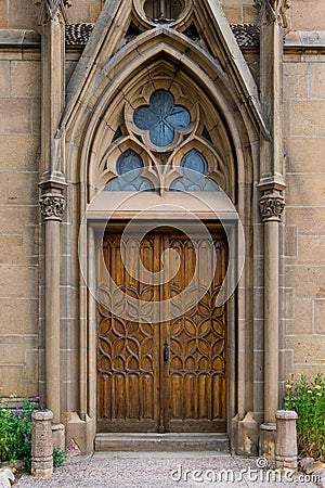 Rustic ornate wood door in a Gothic architecture facade of an old church Stock Photo