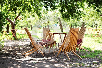 Rustic outdoor furniture for leisure time in nature. Empty chairs and table table in orchard. Autumn courtyard interior with garde Stock Photo