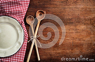 Empty plate, kitchen utensils and red tablecloth on wooden table, top view, copy space Stock Photo