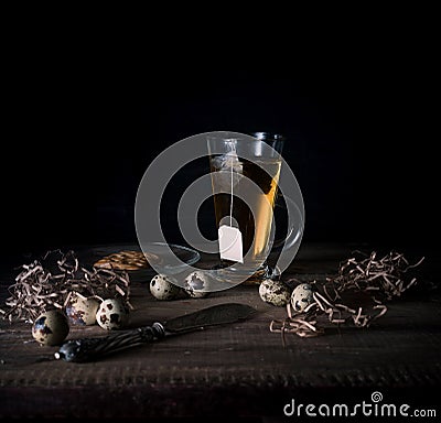 Rustic still life. cup of tea and quail eggs on a wooden table. black background Stock Photo