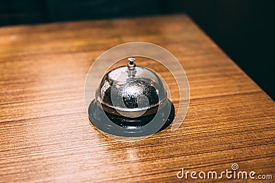 Rustic table bell or call bell on wooden table. For calling waiter Stock Photo