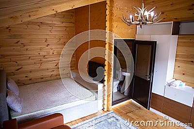 Rustic wooden cabin interior with bed, sofa, and armoire Stock Photo