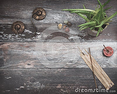 Rustic wooden table with green plant, burning incense, small energy healing stones and Tibetan meditation prayer bells Stock Photo