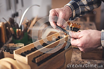 Instrument maker holding a key of a Hurdy Gurdy in his hands Stock Photo