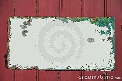 Rusting metal signage screwed to red wood panel fencing Stock Photo