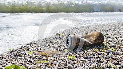 Rusty aluminum can on sea beach discarded sea wave. Garbage pollution of ocean. Metal waste recycling Banner, copy space Stock Photo