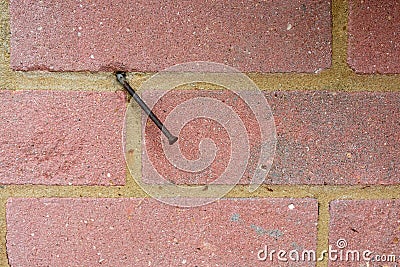 Rusty bent nail in red brick wall Stock Photo