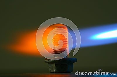 Rusty bolt in a flame of a gas torch. Stock Photo