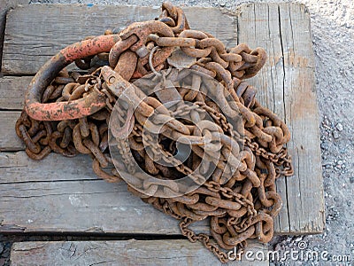 Rusty chain on weathered squared timber. Stock Photo