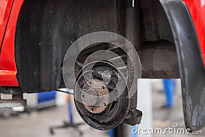 Rusty drum brakes, rear on red car. Change the old to new brake disc on car in a garage. Auto mechanic repairing Stock Photo