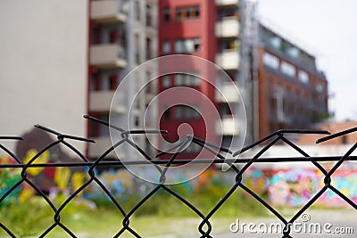 Rusty fence of mesh netting on the background of blurred modern house, the contrast of time. use of old and new materials Stock Photo