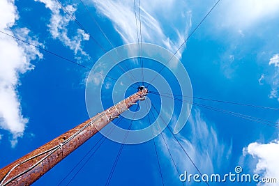 Rusty light pole from below with light cables into blue sky Stock Photo