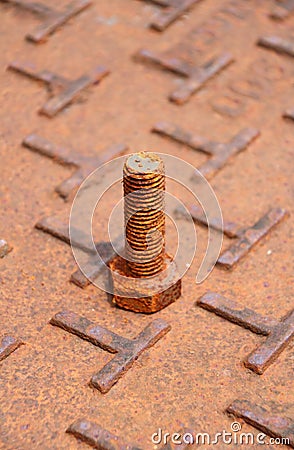 Rusty metal bolt put up on the steel plate floor in brown color with rusty iron. Stock Photo