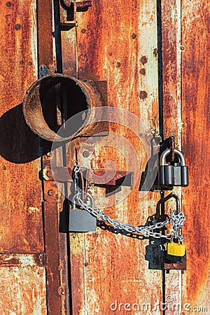 Rusty metallic garage gate locked with padlocks. Sunny close-up view Stock Photo