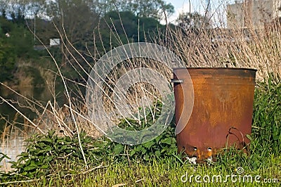 a metal garbage bin on a riverbank with soft focus background Stock Photo