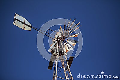 Rusty old farm windmill against blue sky Stock Photo