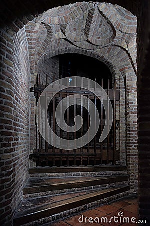 Rusty old fence with sharp points blocks access to a bricked ominous tower Stock Photo
