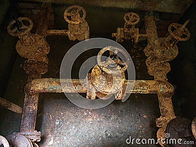 Rusty pipes and valves. Basement of water pumping station. Abandoned post-apocalyptic view of the basement pumping rooms Stock Photo