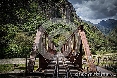 Rusty railway bridge over the river with mountains Surrounding Stock Photo