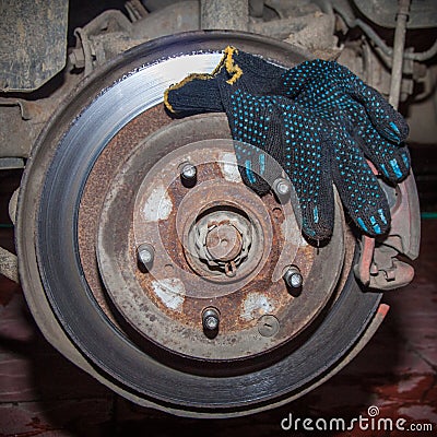 Rusty rear hub of a car wheel with a brake disc and a working black glove. A car without a wheel Stock Photo