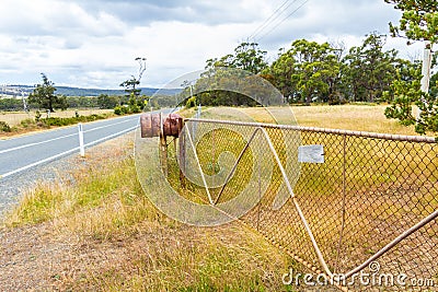 Rusty rural barrel letterbox on farm gate Stock Photo