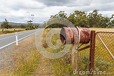 Rusty rural barrel letterbox on farm gate near country road Stock Photo