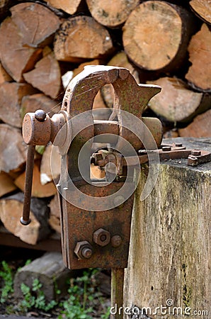 A rusty vice located outside on a stump is used to grip objects for work, also to sharpen a hand scythe. Stock Photo