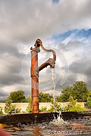 Rusty water tap in sunset light against dramatic skies Stock Photo