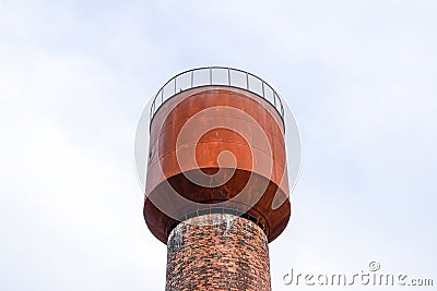 Rusty water tower against sky. Old water pump Stock Photo