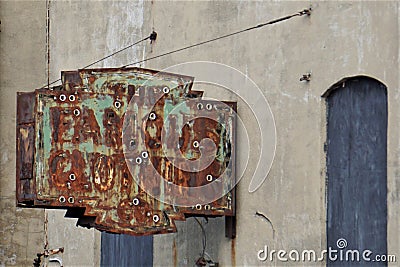 Decrepit rusted vintage sign hanging from building wall Stock Photo