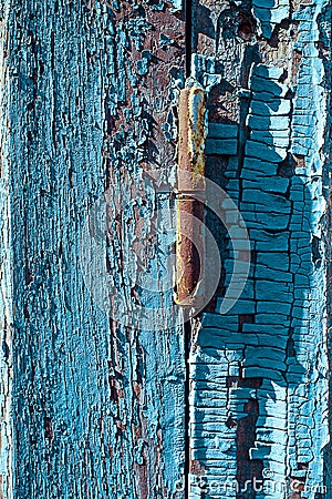 Rusty window hinge on blue wood shutter with cracked and scratch. Vertical grunge wood texture Stock Photo
