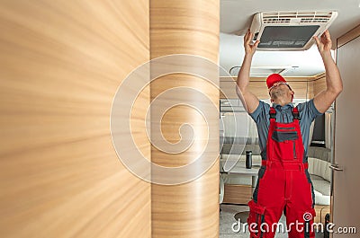 RV Service Worker Replacing or Fixing Travel Trailer Air Condition Stock Photo