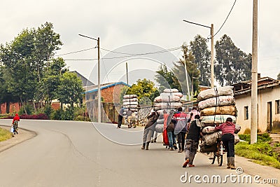 Rwandan farmers men delivering crops from the fields on the bikes loaded with sacks, central Rwanda Stock Photo