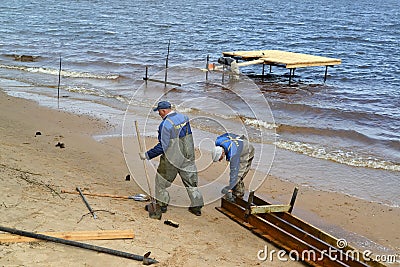 RYBINSK, RUSSIA. Workers prepare designs on construction of a pier in the Rybinsk reservoir. Yaroslavl region Editorial Stock Photo