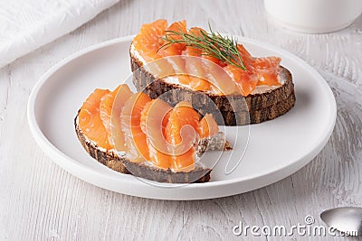 Rye sandwich with salmon and cream cheese on white wooden table Stock Photo