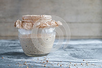 Rye sourdough on whole grain flour in glass jar on table, yeast-free leaven starter for healthy organic rustic bread Stock Photo