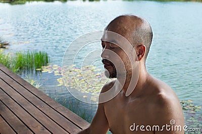 40s bald beard man eye closing mediation with summer blue water lake in wellness relaxation background Stock Photo