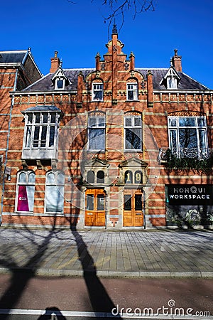 Front view typical dutch red brick gabled houses with shadows of bare trees against blue winter sky Editorial Stock Photo